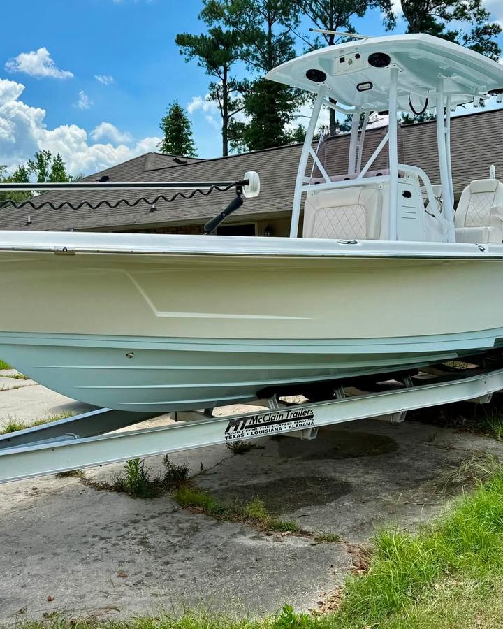 White bay boat with a T-top on its trailer in a driveway after a marine detail