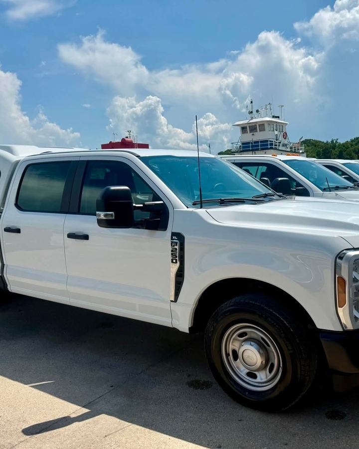 Row of white Ford Super Duty work trucks lined up on a lot after a fleet detail