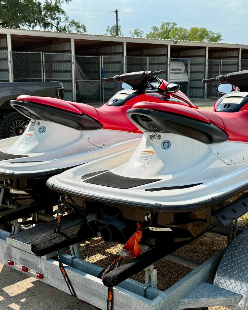 Two red and white Honda jet skis on a double trailer after a detail