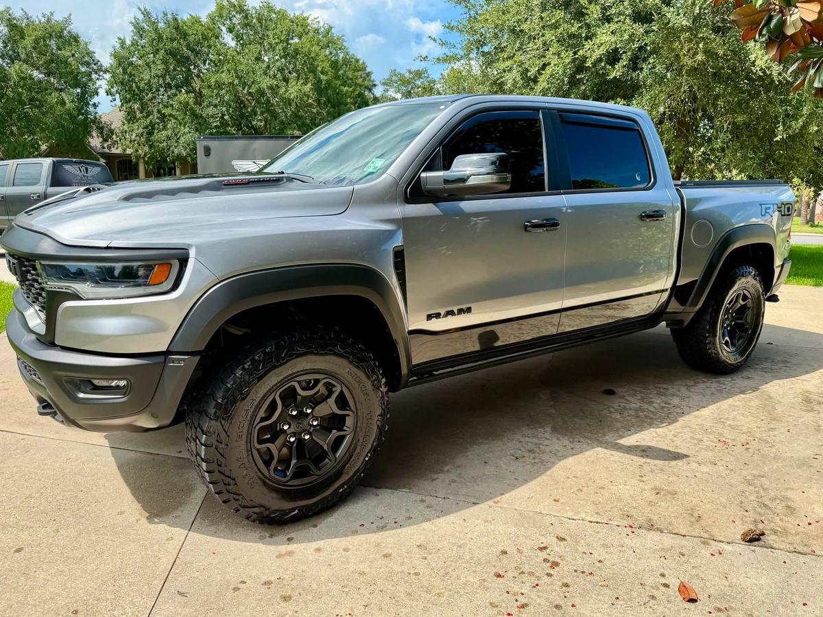 Grey Ram 1500 RHO on off-road tires in a driveway after a detail, paint and wheels spotless